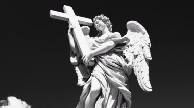 Karanlık gökyüzüne karşı büyük haç tutan mermer melek heykeli, Hıristiyan sanat ve mirasına olan inancı ve korumayı simgeleyen klasik dini heykel.