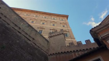 Vatikan 'ın tarihi taş duvarları ve Rönesans mimarisi açık mavi gökyüzü ve dar avludan görülebilen eski savunma tahkimatları.