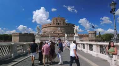 Roma, İtalya, 30 Temmuz 2025 Ponte SantAngelo 'dan SantAngelo Kalesi' ne doğru yürüyen turistler melek heykelleri ve yaz bulutlarıyla çevrili..