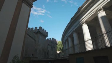 Ortaçağ kale duvarları ve Vatikan 'ın savunma kuleleri St. Peters Meydanı' nın eğimli sütunlarının yanında dağınık bulutlu mavi gökyüzü altında.