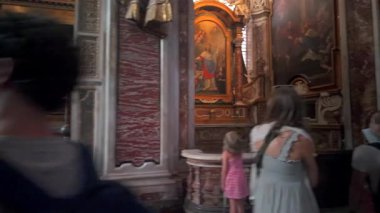 Roma, İtalya, 30 Temmuz 2025 - Ziyaretçiler, tarihi Roma kilisesi içinde tarihi mermer duvarlar ve dini sanat eserleriyle birden fazla Barok tablosu ve heykeli gözlemlediler