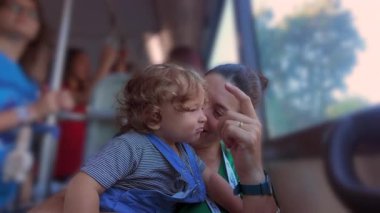 Gülümseyen bir kadın otobüste diğer yolcularla birlikte, aile seyahati ve taşınma sırasında neşeli bir ebeveyn bağı kuruyor.