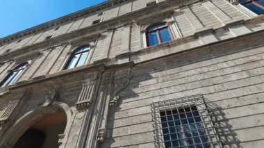 Roma, İtalya 'da kemerli kapı ve pencereli tarihi Avrupa taş binasının alçak açılı görüntüsü, açık mavi gökyüzünün altında klasik mimariyi vurguluyor.