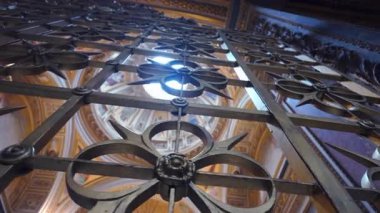 Roma, 31 Temmuz 2025 Süslü demir kapıdan yukarıya doğru melek freskleri ve dairesel tavan penceresinden süzülen güneş ışığıyla bazilika kubbesine doğru.