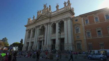 Roma, İtalya, 30 Temmuz 2025 - Roma 'daki St. John Lateran Bazilikası' nın dışı Güneşli bir öğleden sonra tarihi Barok maskaralığının önünde yürüyen turistlerle.