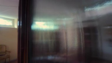 Donmuş cam yüzey boyunca bulanık bir görüş. İç odanın bozulmuş şekillerini gösteriyor. Soyut gizem, derinlik ve yumuşatılmış mimari formları çağrıştırıyor.