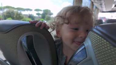 Bebek öne eğilir ve otobüs koltuğunu yalarken arkasını kollar. Yolculuk sırasında garip ve spontane bir duyusal keşif eylemine girişir.