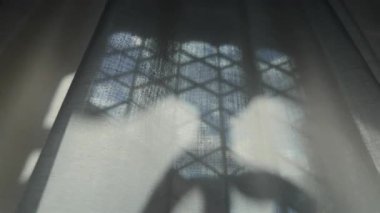 Balpeteği desenli gölgeyi perdenin içinden filtreleyerek geometri, şeffaflık ve katmanlı iç derinliğin soyut etkileşimini yaratıyor.