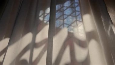 Altıgen pencere çerçevesiyle perdeyi kapat. Güneş ışığı boyunca keskin gölgeler bırak. Mimari geometriyi yumuşak kumaş kıvrımlarıyla harmanla.