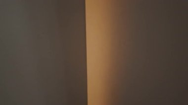 Kırsal koridorda ışığı kapatmak için uzanan bir bakış açısı. Taştan tavan ve beyaz duvarlar var. Çıkışı işaret ediyor.