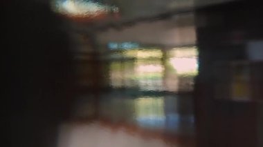 Yayılmış doğal ışık, iç ve pencerenin bulanık şekilleri renkli geometrik desenlerle harmanlanarak dokulu cam duvar boyunca soyut çarpıtılmış görünüm