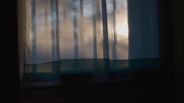 Saf mavi perdelerin arasından süzülen güneş ışığı sessiz, sessiz ve yumuşak gölgeler yaratıyor.