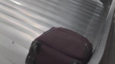 Havalimanı bagajında tekerlekleri olan kestane rengi bavul. Metalik levhalı ve ulaşım terminalinde kıvrımlı kenarlı bir atlıkarınca.