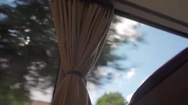 Gündüz yolculuğu sırasında perdeli ve bulanık ağaçlarla otobüs penceresinden bak