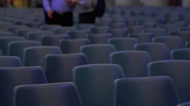 Geniş salonda simetrik sırada dizilmiş sayısız boş mavi sandalyelerin geniş görünümü izleyiciler veya büyük ölçekli olaylar için hazırdır