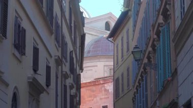 Roma, İtalya 'daki Rönesans Kilisesi' ne uzanan yüksek binalar arasındaki dar dar geçitte sıcak pastel duvarlar, kepenkler ve nostaljik Akdeniz atmosferi var.