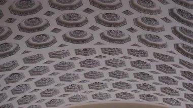 Oktagonal çerçeveler ve ara kare tasarımlar içinde özenle hazırlanmış çiçeklerle dolu tarihi kasalı tavanın geniş mimari manzarası, usta işçiliği vurguluyor.