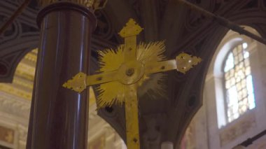 Süslü sütunlara yerleştirilmiş parlak güneş ışığı desenli altın işlemeli haç kemerli pencereler ve dekoratif tavan ile tarihi bazilika içinde sergilenir