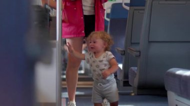 Çocuk, aile içi taşımacılık sırasında ebeveynlerin yanı sıra merak, neşeli keşif ve bağımsızlık anları ile tren koridorunu keşfediyor