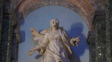 Roma, İtalya, 30 Temmuz 2025 - Kilisenin mavi arka planında kollarını açmış mermer bir aziz heykeli