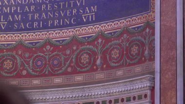 Roma, İtalya, 30 Temmuz 2025 - Roma 'daki Aziz John Lateran Bazilikası' nda çiçek desenleri ve Latince yazıtlı kırmızı ve mavi mozaik duvar