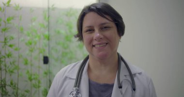 Tıbbi klinikte steteskop takan gülümseyen kadın doktor, hastalara yardım etmeye hazır, dost canlısı ve cana yakın sağlık hizmetleri uzmanı.