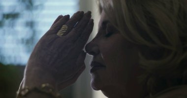 Elleri yüzü kapamış yaşlı bir kadın, gözleri sessiz duygusal keder ya da dua anlarında kapalı.