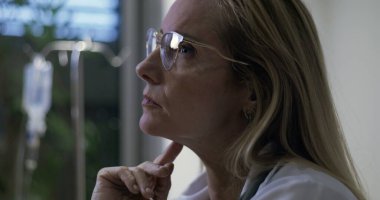 Kadın doktorun yaklaşırken çenesini dinlendirirken, derin düşüncelere dalmış, tıbbi ofisteki sessiz bir anda.