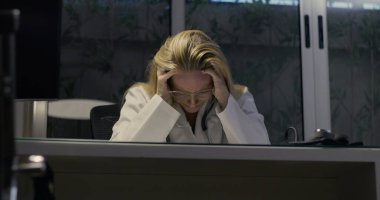 Kadın doktor umutsuzca başını eğiyor. Gece klinikte şiddetli yorgunluk belirtileri gösteriyor.