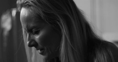 Siyah ve beyaz kadın, duygusal ifadeyle aşağıya bakıyor, klinik çevredeki hassasiyeti ve acıyı yakalıyor.