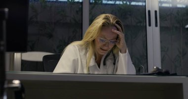 Kadın doktor umutsuzca başını eğiyor. Gece klinikte şiddetli yorgunluk belirtileri gösteriyor.