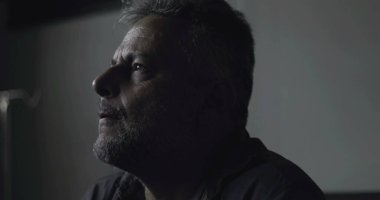 Karanlık klinikte eli yüzü kapalı sıkıntılı bir adamın yakın çekimi, teşhislere karşı duygusal tepki ya da düşük ışıkta yakalanan iç kargaşa