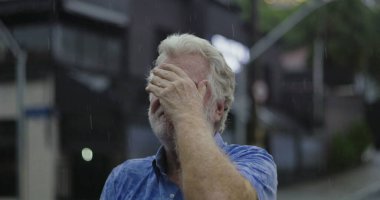 Yüzü tamamen yağmura bulanmış yaşlı bir adam duygusal çöküntü ya da çaresizlik anlarını ifade ediyor.