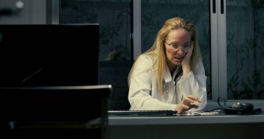 Kadın doktor gece geç saatlere kadar çalışırken masaya yaslanıyor. Yorgun ve bitkin görünüyor.