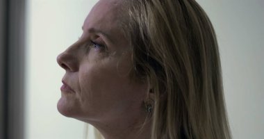 Kadın doktorun sakin klinik alandaki profili, derin düşüncelere daldığı anda ciddi ve odaklanmış bir ifadeyle ileriye bakıyor.