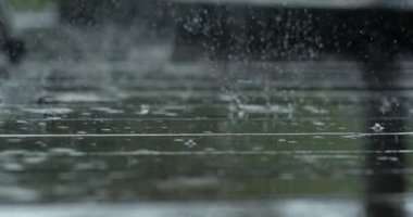 Yağmur damlaları yansıtıcı döşeme tahtalarında dramatik su patlamaları yaratıyor. Yüksek hızlı kamerayla, yumuşak bulanık ve soluk renklerle süper yavaş çekimde çekiliyor.