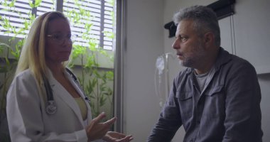 Klinikteki tıbbi muayene sırasında orta yaşlı erkek hastaya zor teşhisler koyan kadın doktor.