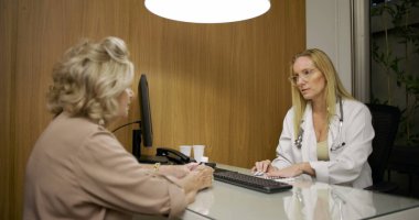 Klinikteki rehberlik oturumunda ilaç kullanımını, masada reçeteli paketlerle anlatan kadın doktor.