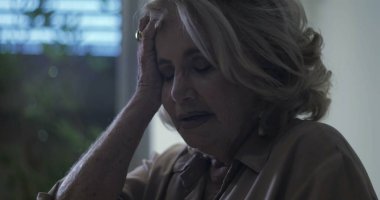 Yaşlı kadın el ele dinleniyor, gözleri kapalı duygusal yorgunluk anında ya da iç karışıklıkta.