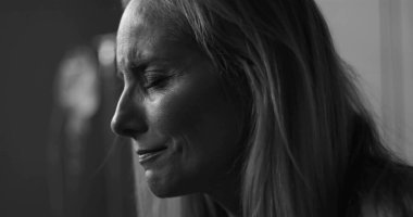 Siyah ve beyaz kadın, duygusal ifadeyle aşağıya bakıyor, klinik çevredeki hassasiyeti ve acıyı yakalıyor.