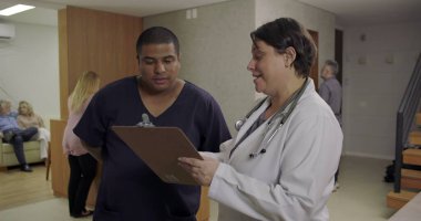 Doktor ve hemşire hastane koridorunda hasta çizelgesini birlikte gözden geçiriyorlar. Her gün yoğun odaklanma ve tıbbi ekip çalışması ile birlikte.