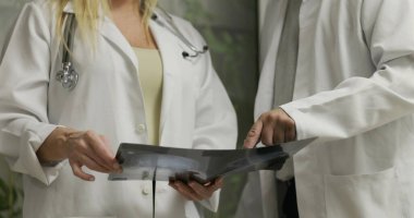 Doktorlar, hastane ortamında odaklanmış ifadeler ve işbirlikçi takım çalışmasıyla klinik teşhis sırasında röntgen sonuçlarını inceleyip tartışıyorlar.