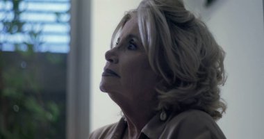 Yaşlı kadın yukari yukari yukari bakiyor, nazikçe dusunuyor, yumusak isik pencerenin yaninda duruyor, gozler duygu ve sessiz güçle dolu.