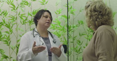 Doktor modern klinik muayenesinde yaşlı kadına teşhis koymak için el hareketi yapıyor.