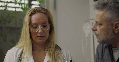 Profesyonel bir iç sağlık hizmetleri ortamında tıbbi danışma sırasında hastanın yanındaki panoya notlar yazan doktorların yakın çekimleri