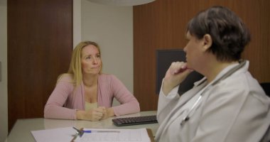 Klinikteki masadaki düşünceli tartışmalar sırasında doktorlara sağlık sorunlarını açıklayan orta yaşlı bir hasta.