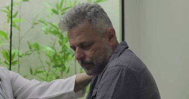 Muayene sırasında zor teşhislere tepki veren orta yaşlı erkek hastaların yakın çekimleri, klinik ortamlarda doktor tarafından desteklenirken duygusal tepkiler