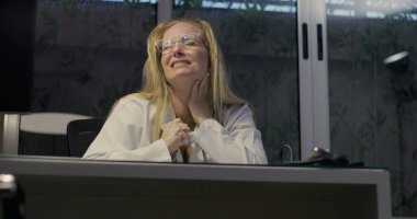 Yorgun kadın doktor, masa başında oturuyor. Uzun bir vardiyadan sonra bunalmış ve stresli. İş yerinde bitkinlik ve yorgunluğun duygusal ifadesi.