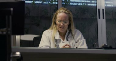 Kadın doktor umutsuzca başını eğiyor. Gece klinikte şiddetli yorgunluk belirtileri gösteriyor.