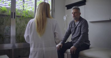 Klinikteki tıbbi muayene sırasında orta yaşlı erkek hastaya zor teşhisler koyan kadın doktor.